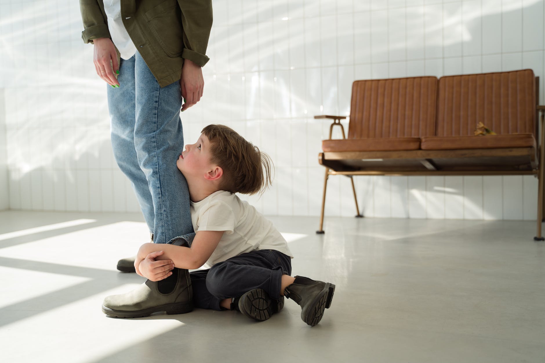 boy sitting on the floor while hugging a person s leg