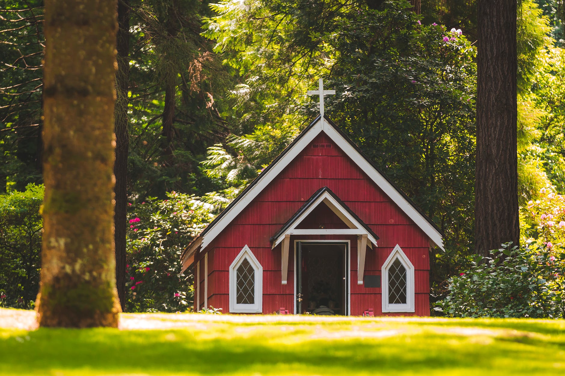 red chapel on grassy field with trees