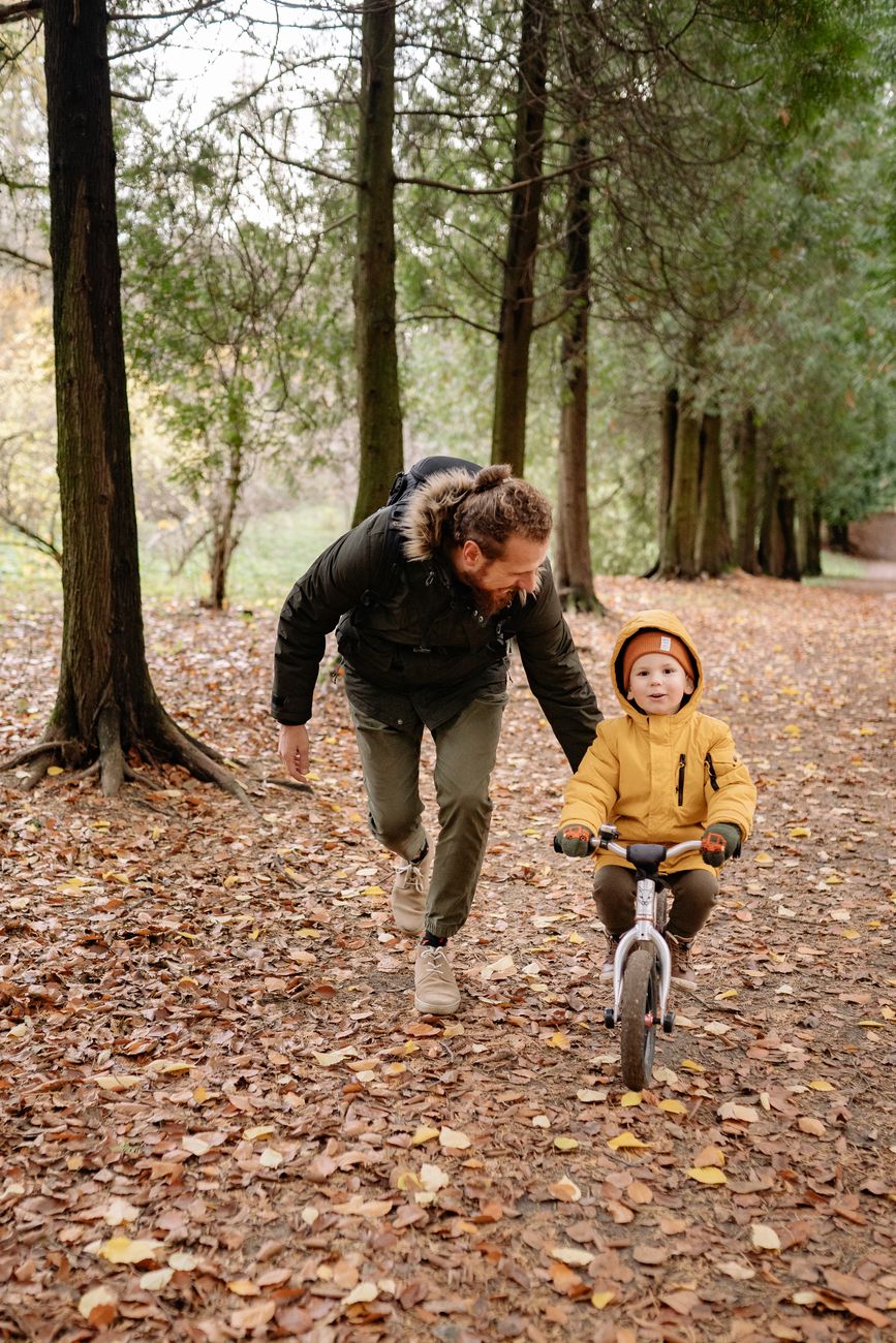 boy riding bike with father help